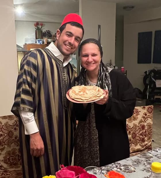Rabbi Adam Abergel and Rebecca Abergel holding a plate of mofletta at Mimouna.